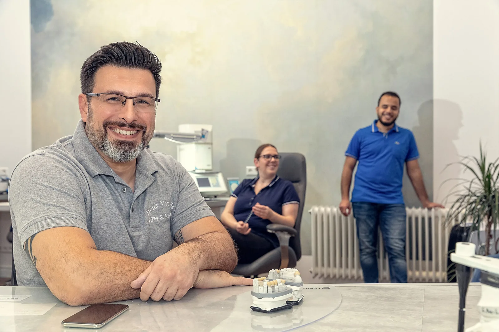 Zahntechnikermeister Selçuk Kocagil im Gespräch, dahinter das Team
