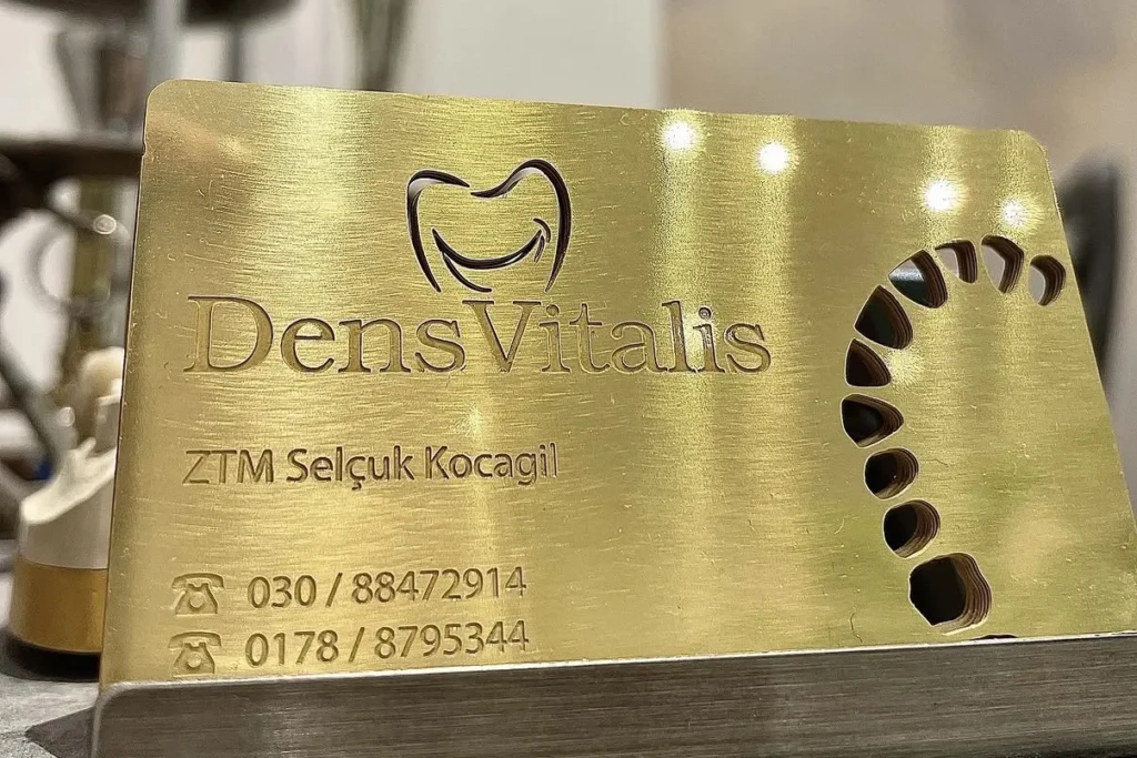 Messingschild mit dem Zeichen von Dens Vitalis, dem Namen von ZTM Selçuk Kocagil und den Rufnummern des Labors